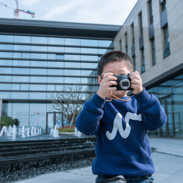 Front view close up on caucasian boy four years old using digital camera taking pictures modern technology growing up and learning developing skills leisure activity