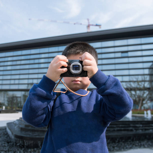 istock A cute little boy holding a camera is taking photos 2083574367