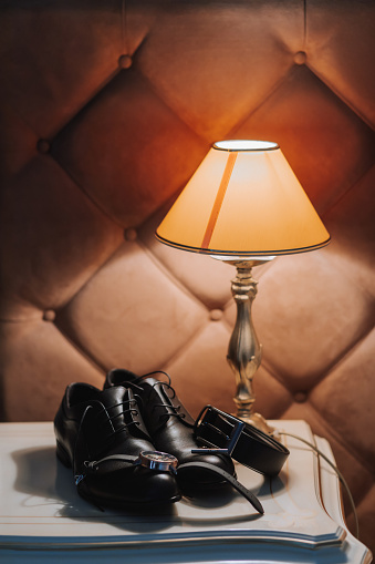 Morning of the groom and details, details of the groom in black on the table under the table lamp.