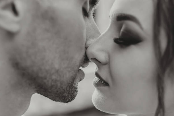 sinnliches paar in zärtlicher leidenschaft. nahaufnahme porträt einer frau, die im begriff ist, einen mann zu küssen. verliebtes paar küsst sich. sexy lippen. schwarz-weiß-foto - passion kissing black white stock-fotos und bilder