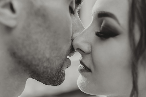 Sensual couple in tender passion. Close-up portrait of a woman about to kiss a man. Couple in love kissing. Sexy lips. Black and white photo