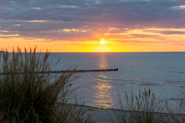 istock Sunset over the sea, with sand dunes and  blurred beach grass 2083578077