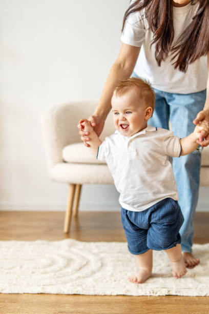 istock Woman holding babys hand on rug 2083581430