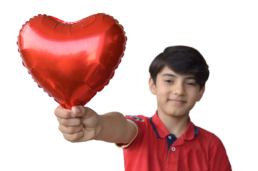 Horizontal shot of cutout of one cute boy's hand holding inflated fun love, valentine, anniversary theme red heart shaped foil balloon in a fist isolated over white background with copy space