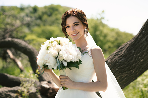 Beautiful bride with a wedding bouquet in the spring forest.