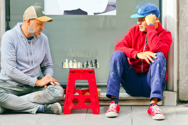 Two men playing chess sitting on ground in the street. Lugo city, Galicia, Spain.