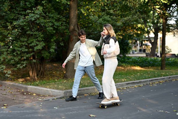 istock Guy teaches girlfriend to skateboard in the park 2083637737