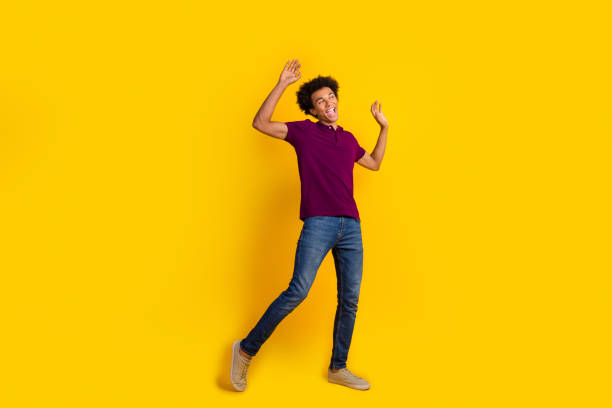 istock Photo of glad optimistic man wearing trendy purple clothes dancing looking empty space banner isolated on yellow color background 2083665310