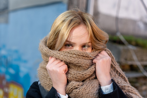 Beautiful blonde woman covers her face with a scarf