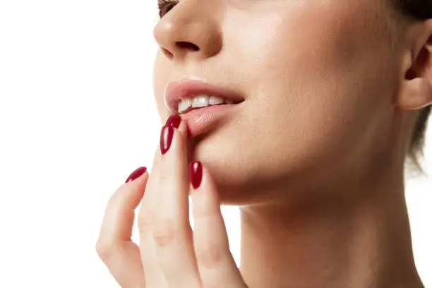 Close up beautiful woman with bare shoulders applying lipbalm on lips against white studio background. Lipcare. Concept of natural beauty people, injections, wellness, spa procedures, cosmetology. Ad