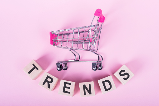 TERNDS - word on wooden cubes, on a pink background with a shopping trolley.