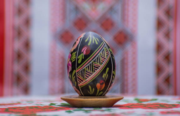 Isolated traditional Easter egg colored with onion peel in brown color, with flower pattern, isolated colored brown Easter egg on white background, Easter holiday table decoration, copy space