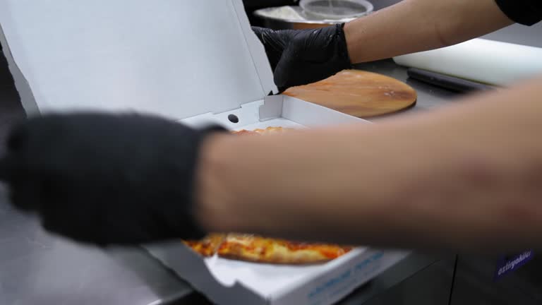 Chef stacking pizza in cardboard box for delivery to customer