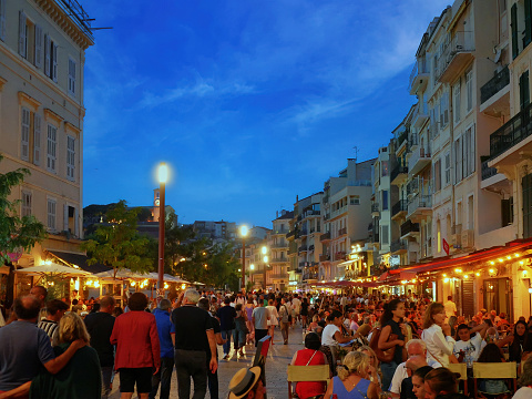 Cannses, France - June 2022: Street restaurants in Cannes Tourists visit local shops at dusk or night