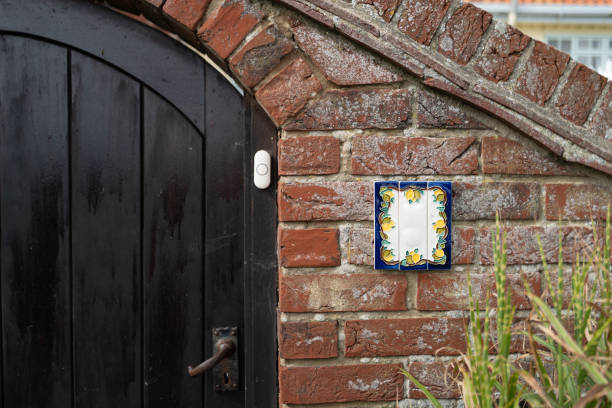 Blank, french-style ceramic house number plate seen fixed to the front entrance porch to an English seaside property. Blank, french-style ceramic house number plate seen fixed to the front entrance porch to an English seaside property. The brick archway leads to the main house. ceramic tile house numbers stock pictures, royalty-free photos & images