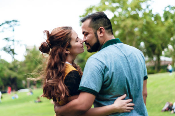 młoda latynoska para heteroseksualna ciesząca się przytulaniem w parku. - contreras zdjęcia i obrazy z banku zdjęć