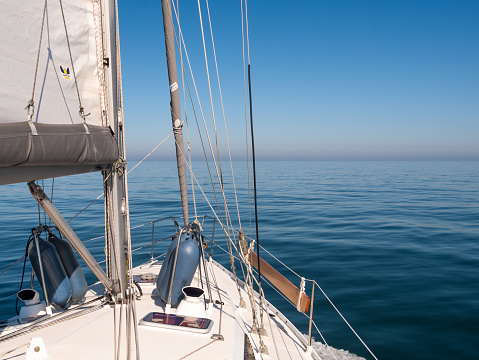 Sailboat sailing on calm sea with light winds under clear blue sky, German Bight, North Sea near coast of Jutland, Denmark
