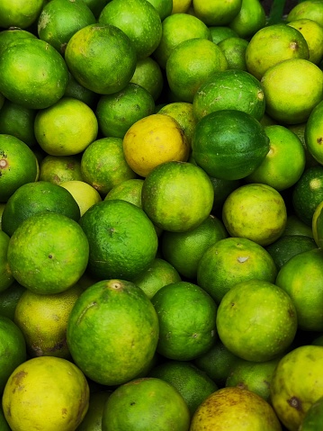 Fresh limes stacked at a grocery store fruit stand