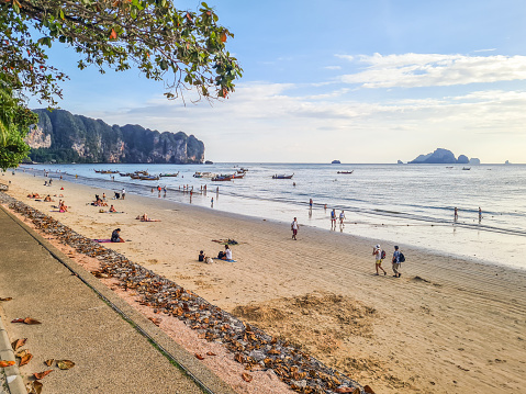 Krabi, Thailand - January 3, 2024 : People walking and relaxing at the sandy Ao Nang beach on the Andaman sea in Thailand.