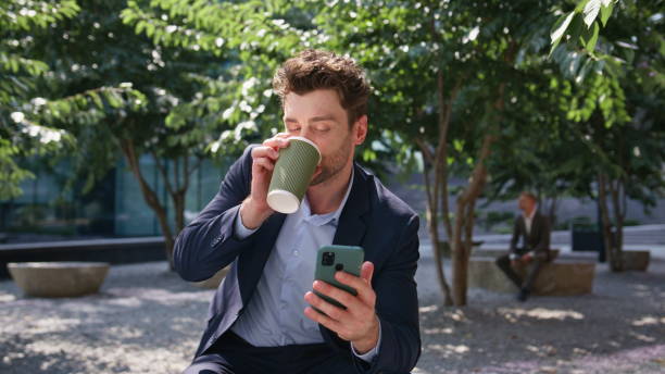 istock Relaxed employee drinking coffee looking smartphone on sunny park close up. 2083810568