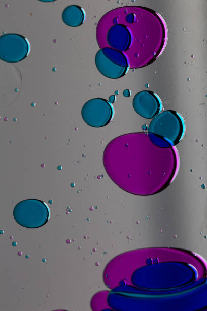 Colored oil bubbles grey background primary colors purple and blues floating in water