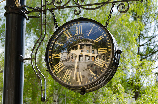 Large vintage round clock in the city park in summer