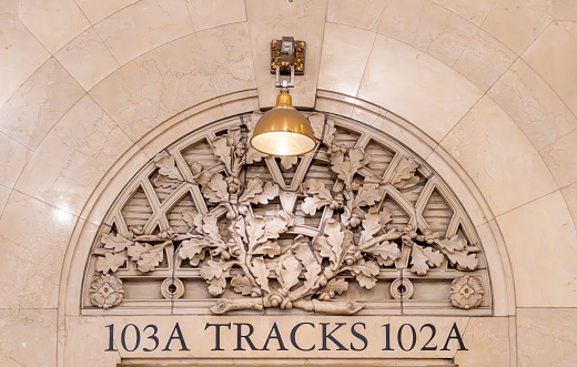 A carved stone architrave and track number sign inside Grand Central station, New York City, USA.