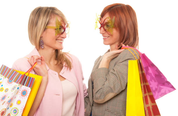 Two Smiling young women friends shopping for summer clothes together at outdoor flea market