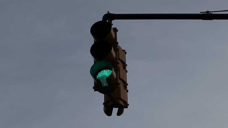 traffic light turning green and swaying in the breeze (against bright blue sky)