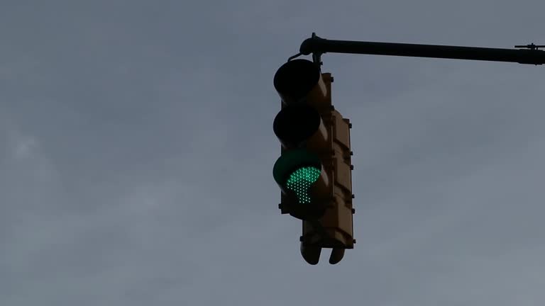 traffic light turning green and swaying in the breeze (against bright blue sky)