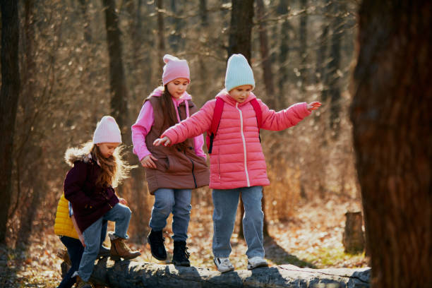 istock Little kids in winter attire playing and balancing on fallen tree trunk. Leisure activity. Outdoor activities for children's development. 2083861616