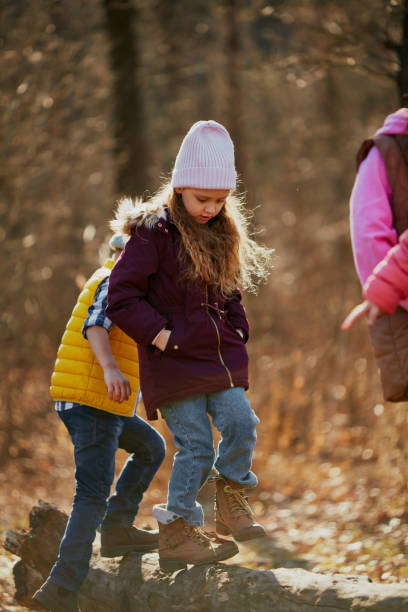 istock Little explorers, schoolboys and girls, walking across log, practicing balance in sun-drenched forest. Outdoor activities for children's development. 2083861618