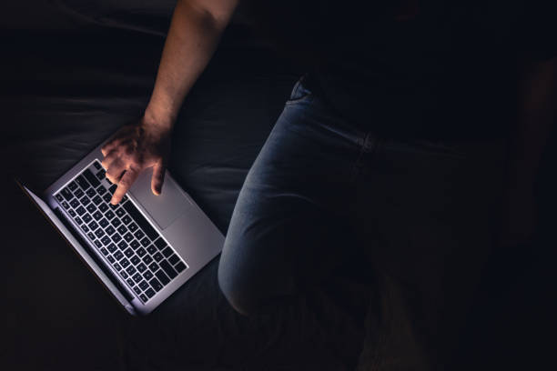Businessman or freelancer working overtime with laptop at home, lying on sofa late at night, has deadline at work. Insomnia and computer addiction.