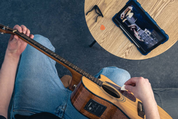 istock A man learns to play the guitar using a tablet, top view. 2083872316