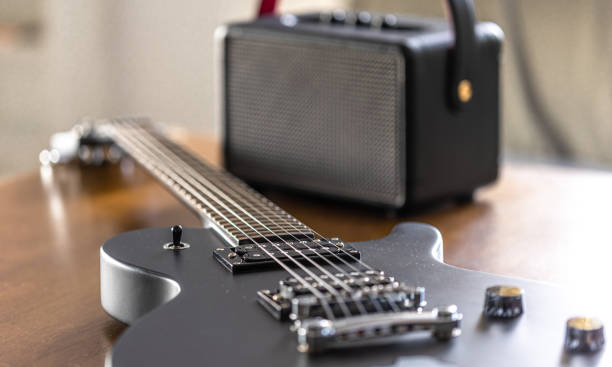 Black electric guitar and speaker on a wooden table. Guitar and amplifier, close-up.