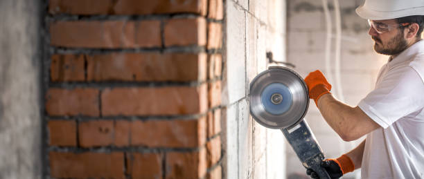 istock Builder works with a angle grinder to cut bricks and build interior walls. 2083915960