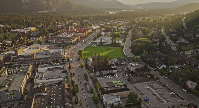 Banff AB Canada Aerial v20 birds eye view flyover Bow river across the town along the Banff avenue capturing quaint townscape and forested valleys at sunrise - Shot with Mavic 3 Pro Cine - July 2023