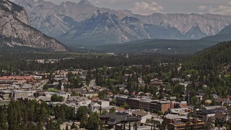 Banff AB Canada Aerial v40 zoomed shot drone flyover forested valley capturing picturesque landscape of quaint town nestled amidst towering mountain ranges - Shot with Mavic 3 Pro Cine - July 2023