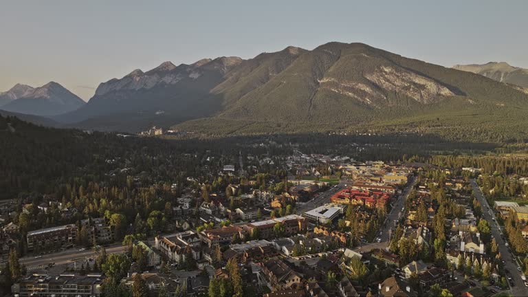 Banff AB Canada Aerial v21 flyover residential area and mountain township capturing picturesque townscape, forested valley and mountainous landscape at sunrise - Shot with Mavic 3 Pro Cine - July 2023