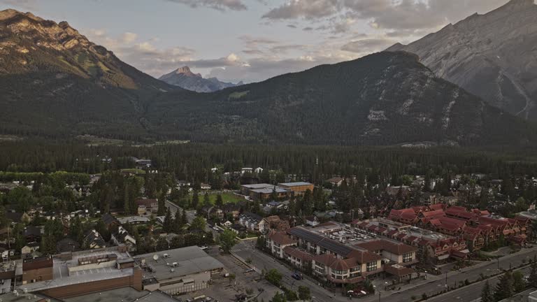 Banff AB Canada Aerial v12 cinematic drone flyover town center capturing quiet morning streets, lush forested valley and Cascade mountain ranges at sunrise - Shot with Mavic 3 Pro Cine - July 2023