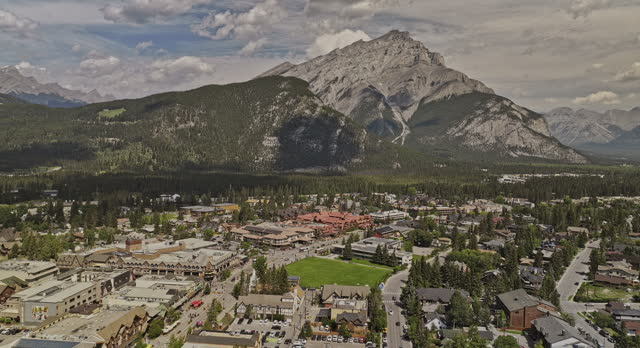 Banff AB Canada Aerial v34 drone flyover forested valley across Bow river and town center capturing picturesque townscape and Cascade mountain ranges in summer - Shot with Mavic 3 Pro Cine - July 2023