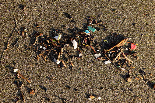 A pile of trash on the beach. The trash is made up of plastic and wood. Concept of pollution and the need for environmental awareness