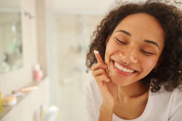 istock a woman is smiling while looking at her face in the mirror 2083946160