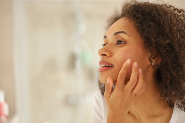 istock a woman is looking at her face in the mirror 2083967462