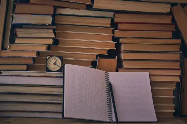 Photo of Notebooks and black pencil against a wall of folded n books