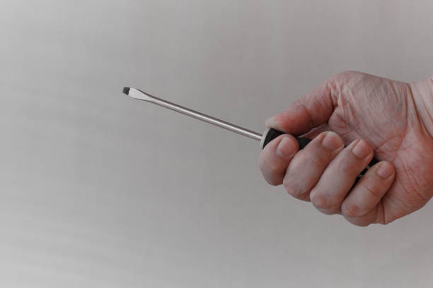 istock A man's hand holds a screwdriver as if for an attack, close-up on a white background 2084012053