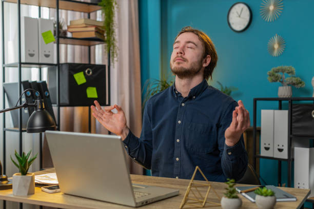 istock Peaceful relaxed businessman sitting at workplace with folded in mudra gesture hands meditating 2084040494