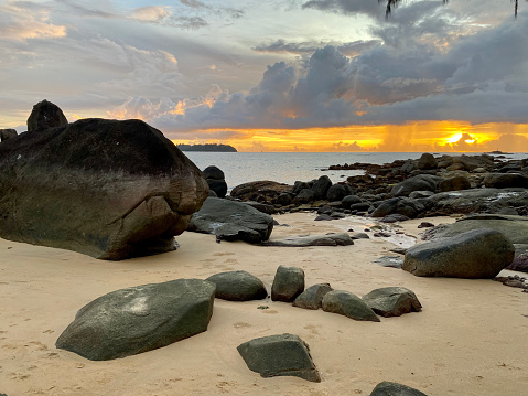 Sunset on Thai beach with rocks and amazing clouds