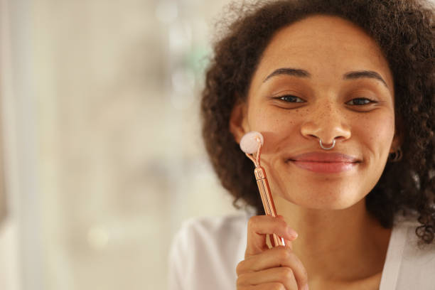 istock A woman is using a rose quartz roller on her Forehead, Cheek, and Jaw 2084049118