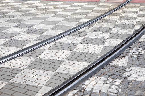 Tram tracks across a chequered road surface in the city of Brussels, Belgium